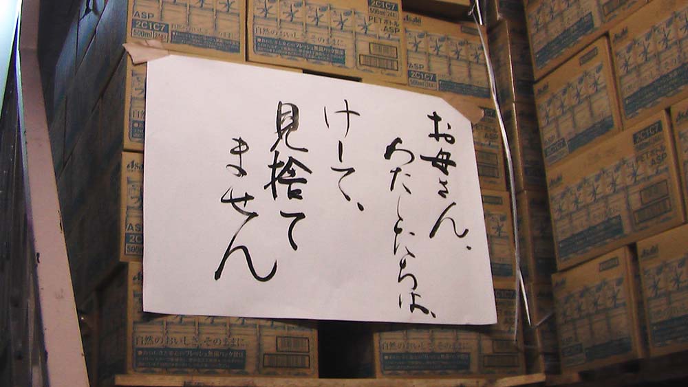2013年方八町倉庫。たくさんの水が積まれている箱に、坪井が書いたメッセージ。